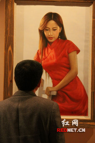 (湘籍实力派油画家唐三超的作品首次回乡展出，图为一名观众在欣赏其作品。)